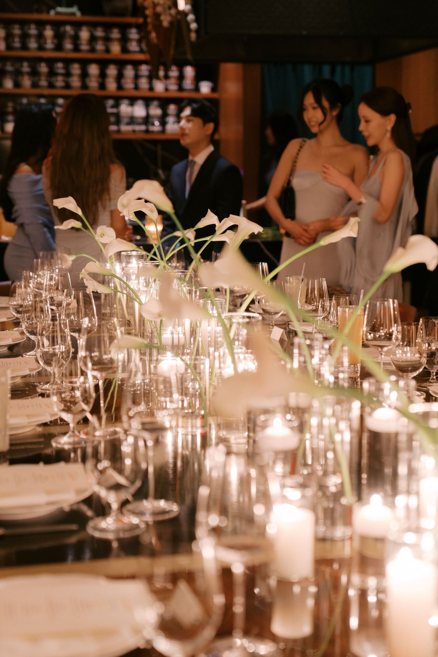 Romantic candlelit wedding reception table with glowing votives and place settings creating ambient lighting.