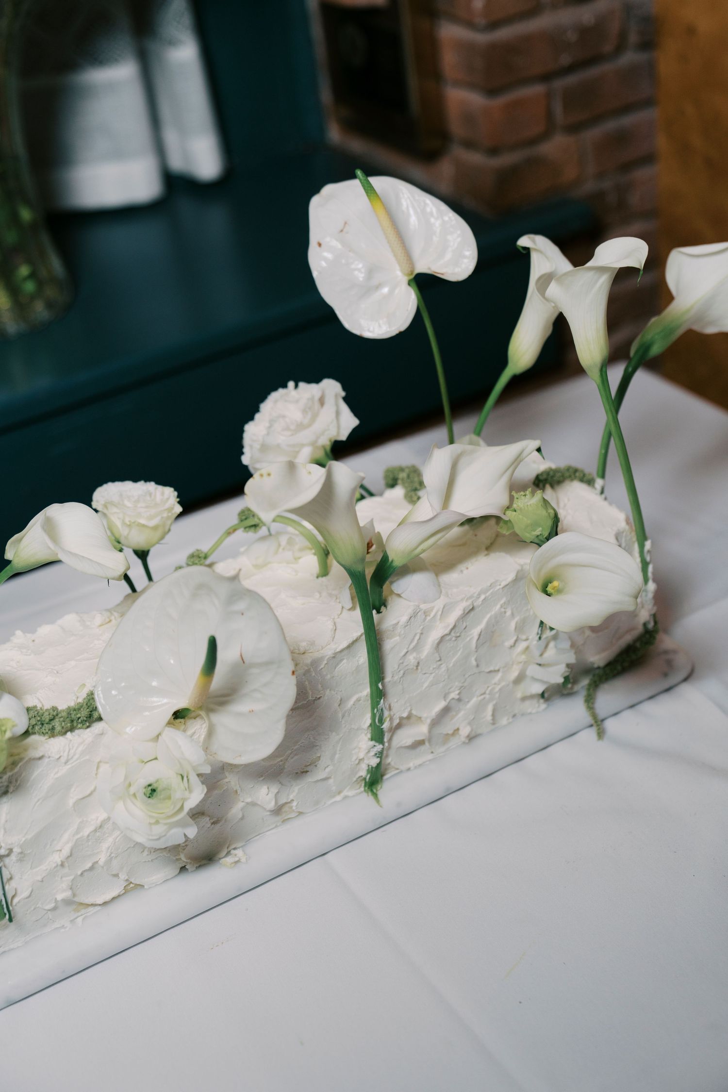 White floral arrangement with roses and anthuriums displayed on a light surface.