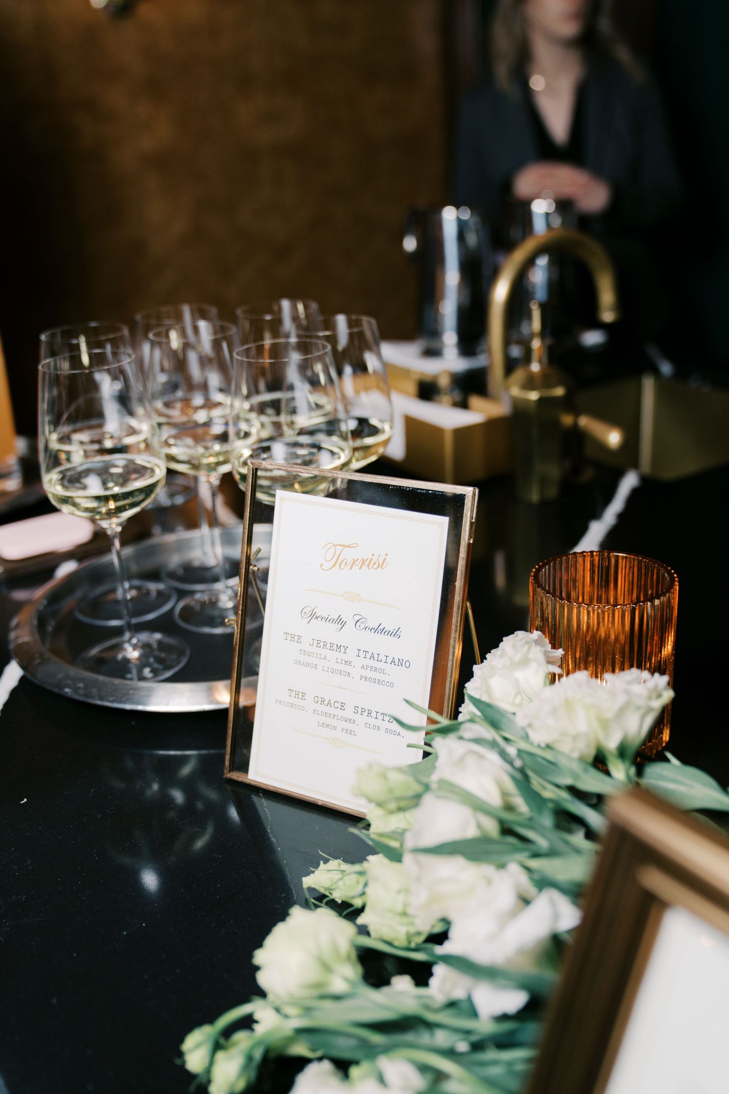 Elegant table settings with wine glasses, name cards and white floral arrangements at a formal dining event.