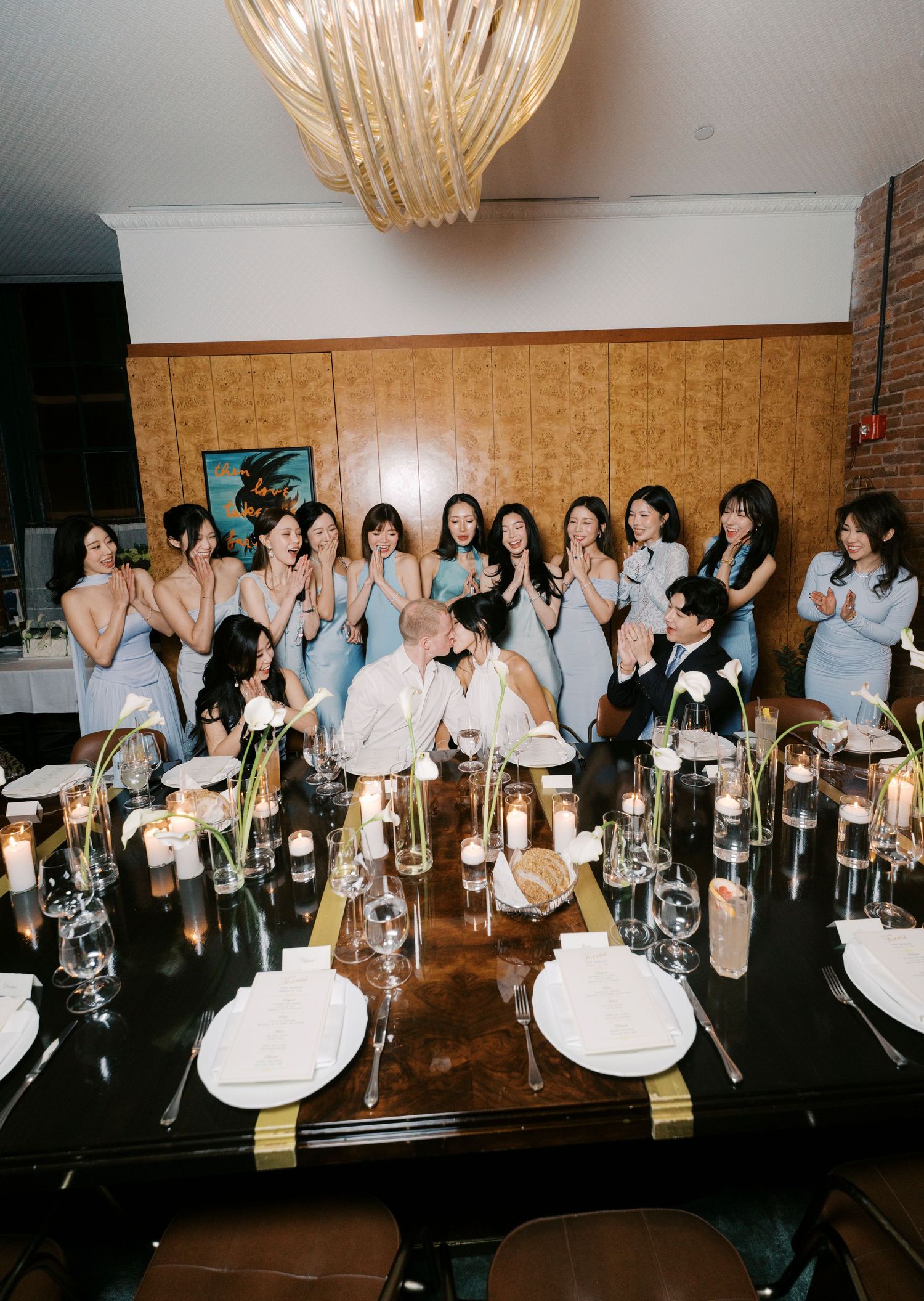 A group of people seated at a long dining table with wine glasses and place settings in a banquet room.