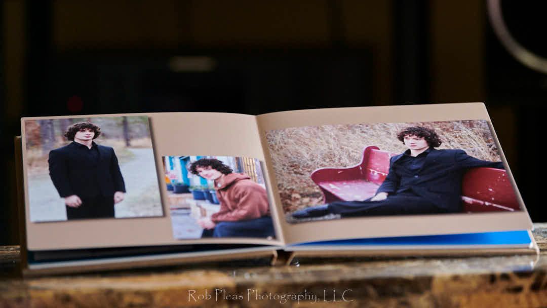 Second image of high school senior male's photos in linen album.  Album is resting on coffee table in front of stereo system.