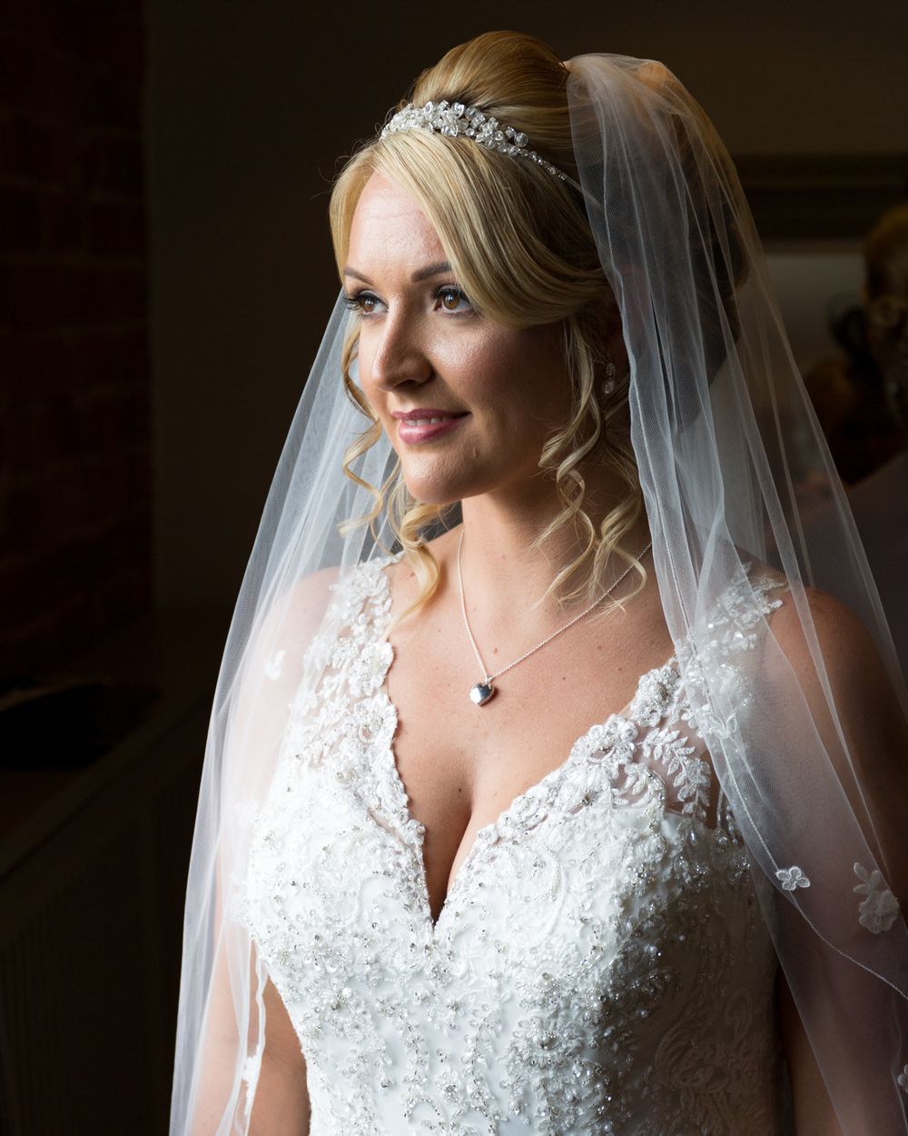 Close-up detail of an elegant white lace wedding dress with delicate beading and veil.