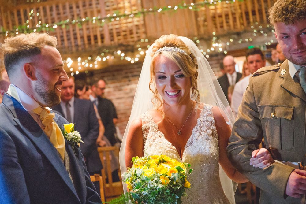 Wedding reception guests mingling and celebrating with drinks and yellow floral decorations.