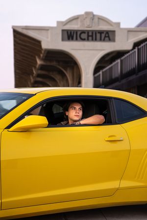 Bright yellow sports car parked in front of a building with Wichita signage visible in the background.
