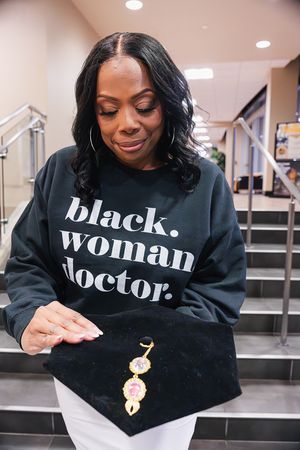 A series of five photos showing someone wearing a black sweatshirt with white text while holding a small gold charm.