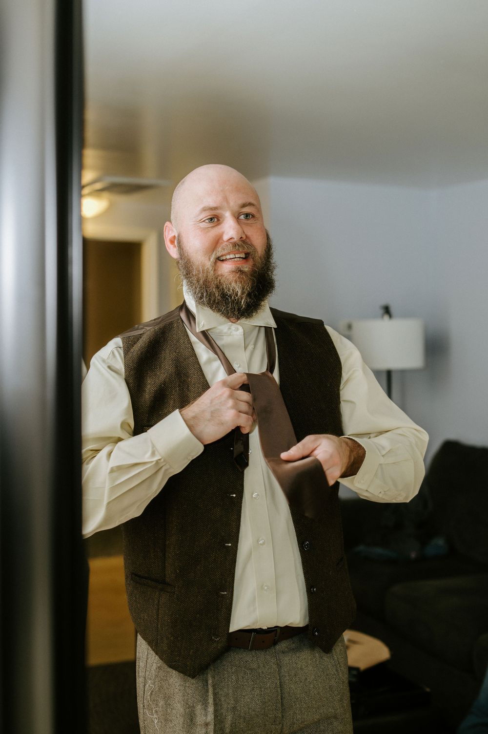 A series of expressive portraits showing someone adjusting their tie while wearing a dark vest and light colored shirt.