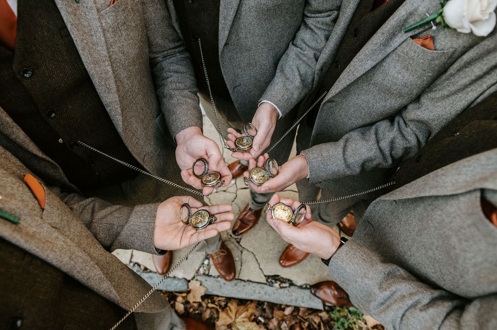 Hands holding shot glasses together in a celebratory toast wearing gray formal attire.