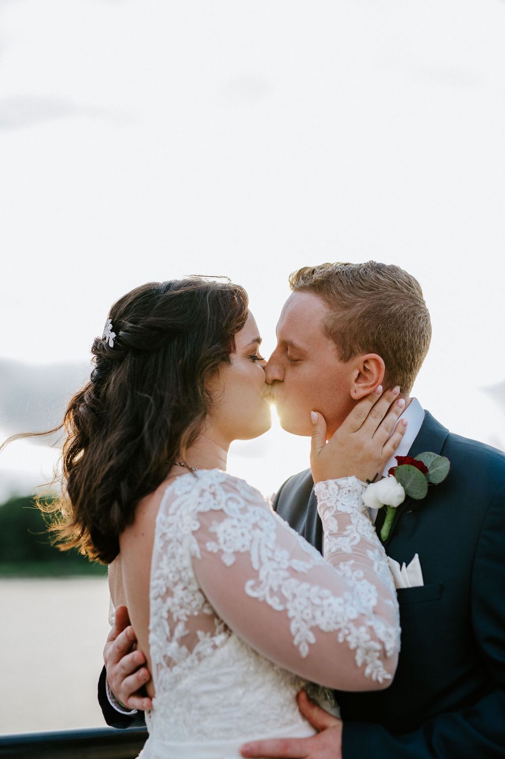A romantic moment captured on a cloudy day with a couple in wedding attire embracing.