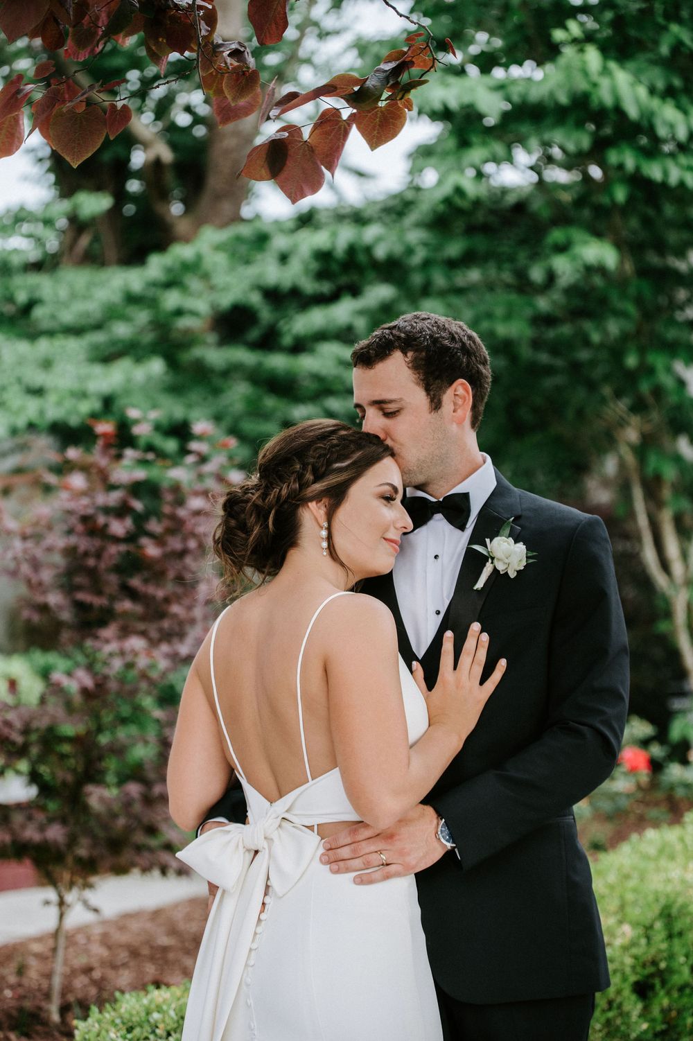 A romantic wedding moment captured in a lush garden setting with soft natural lighting and elegant formal attire.