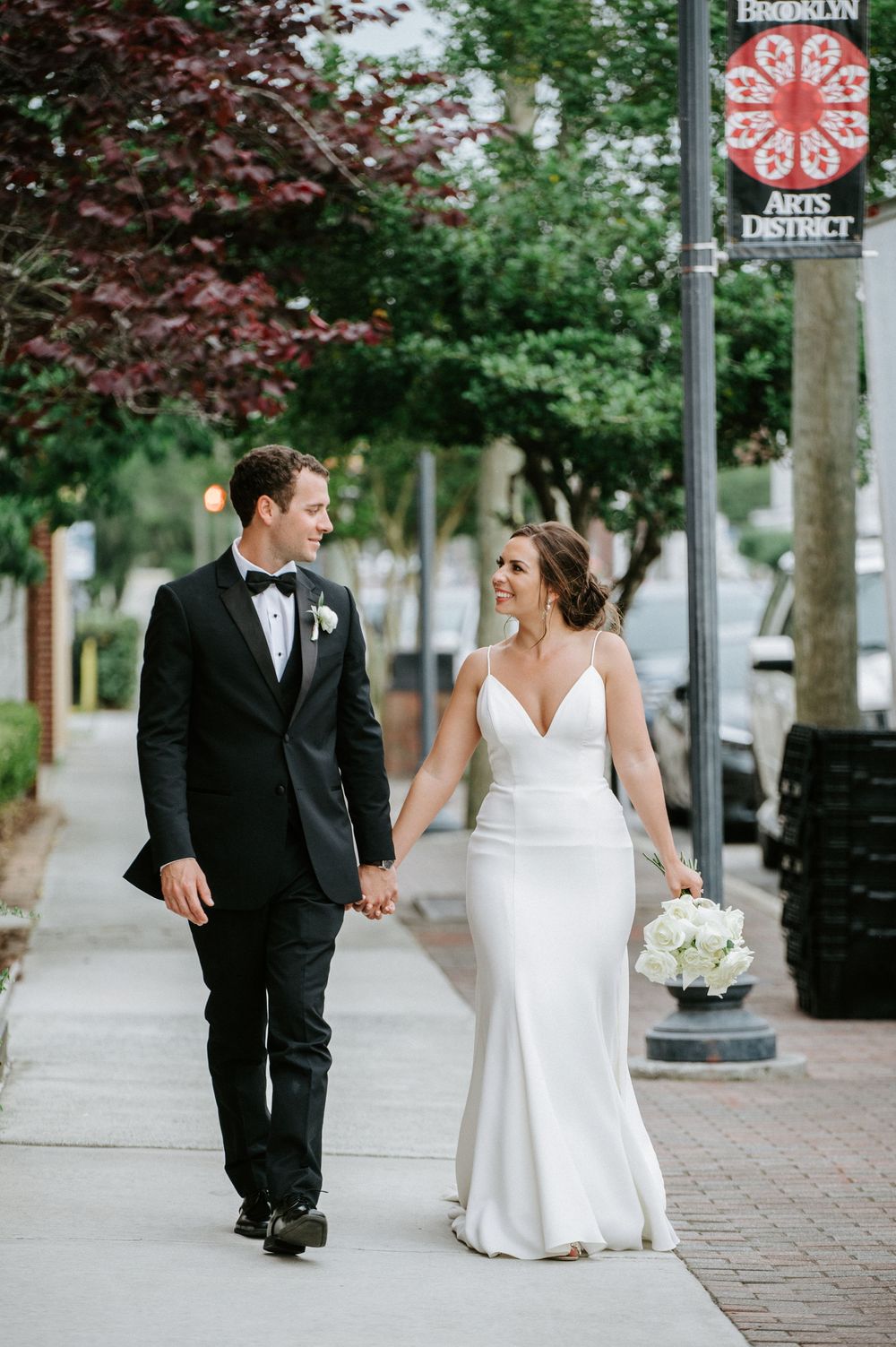A newlywed couple walks down a brick sidewalk in Brooklyn's Arts District on their wedding day.
