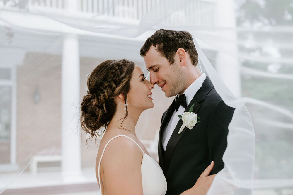 A romantic wedding moment captured as newlyweds share an intimate embrace in front of a white building.