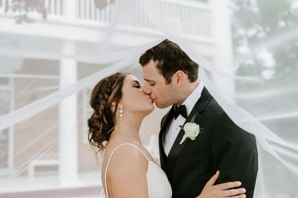Romantic couple sharing a tender kiss during their wedding ceremony in a light-filled setting.