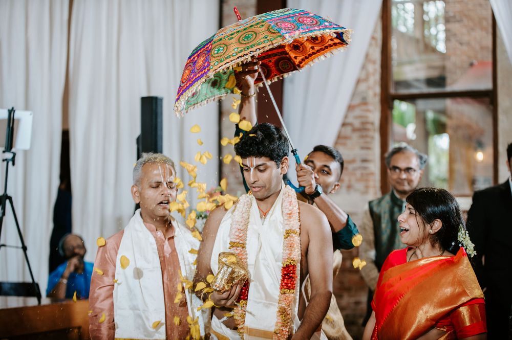 Traditional Indian wedding ceremony with colorful umbrellas and decorative elements during an indoor celebration.