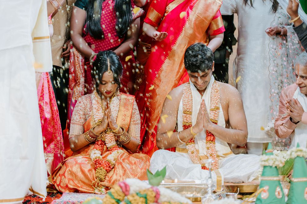 Celebratory scene with colorful decorations and guests throwing rice and flower petals during a traditional Indian ceremony.