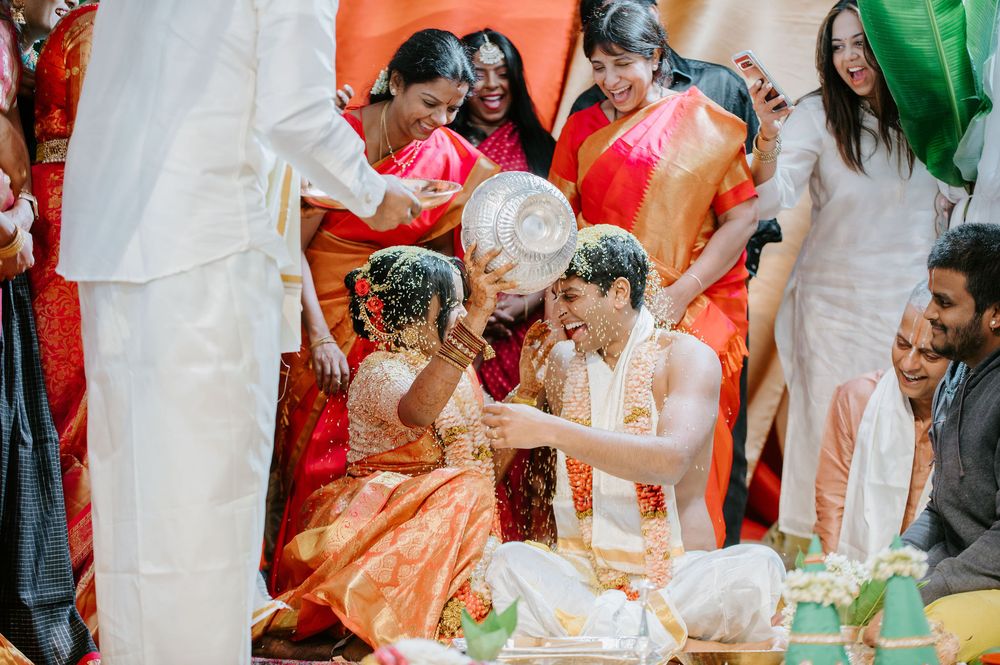 Traditional Indian wedding ceremony with guests seated around a decorated mandap in orange and white.