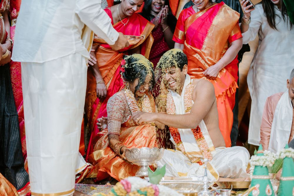 Ceremonial moment during traditional Indian wedding with guests in vibrant orange and pink attire.