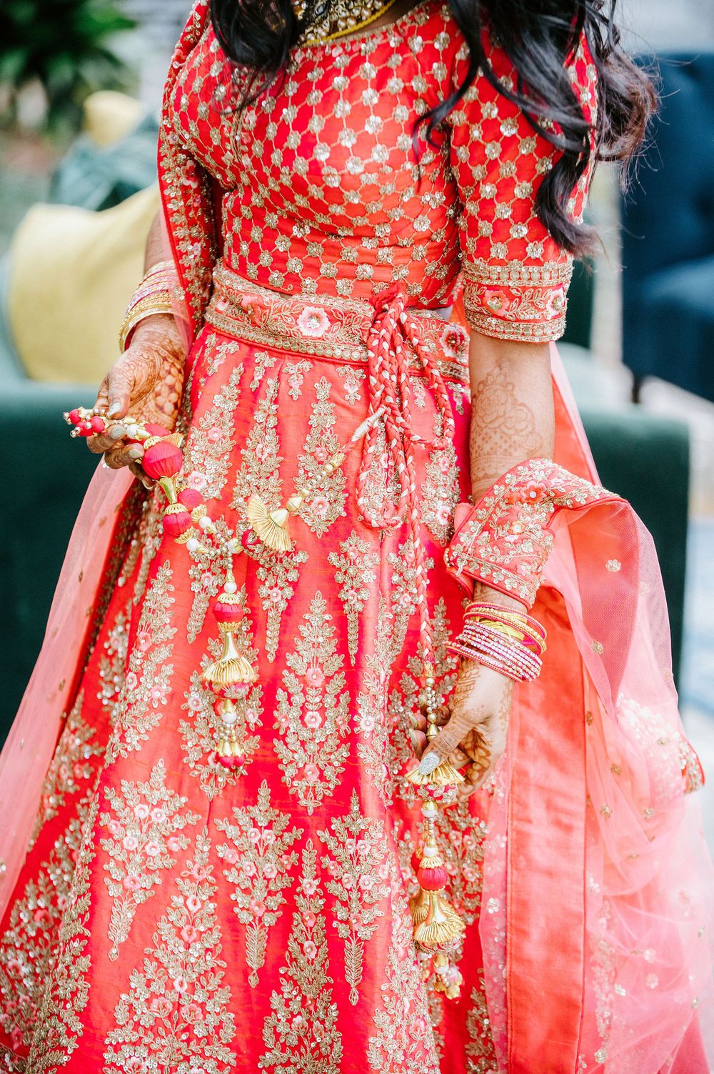 Detailed view of a red and gold embroidered Indian bridal lehenga with intricate traditional patterns.
