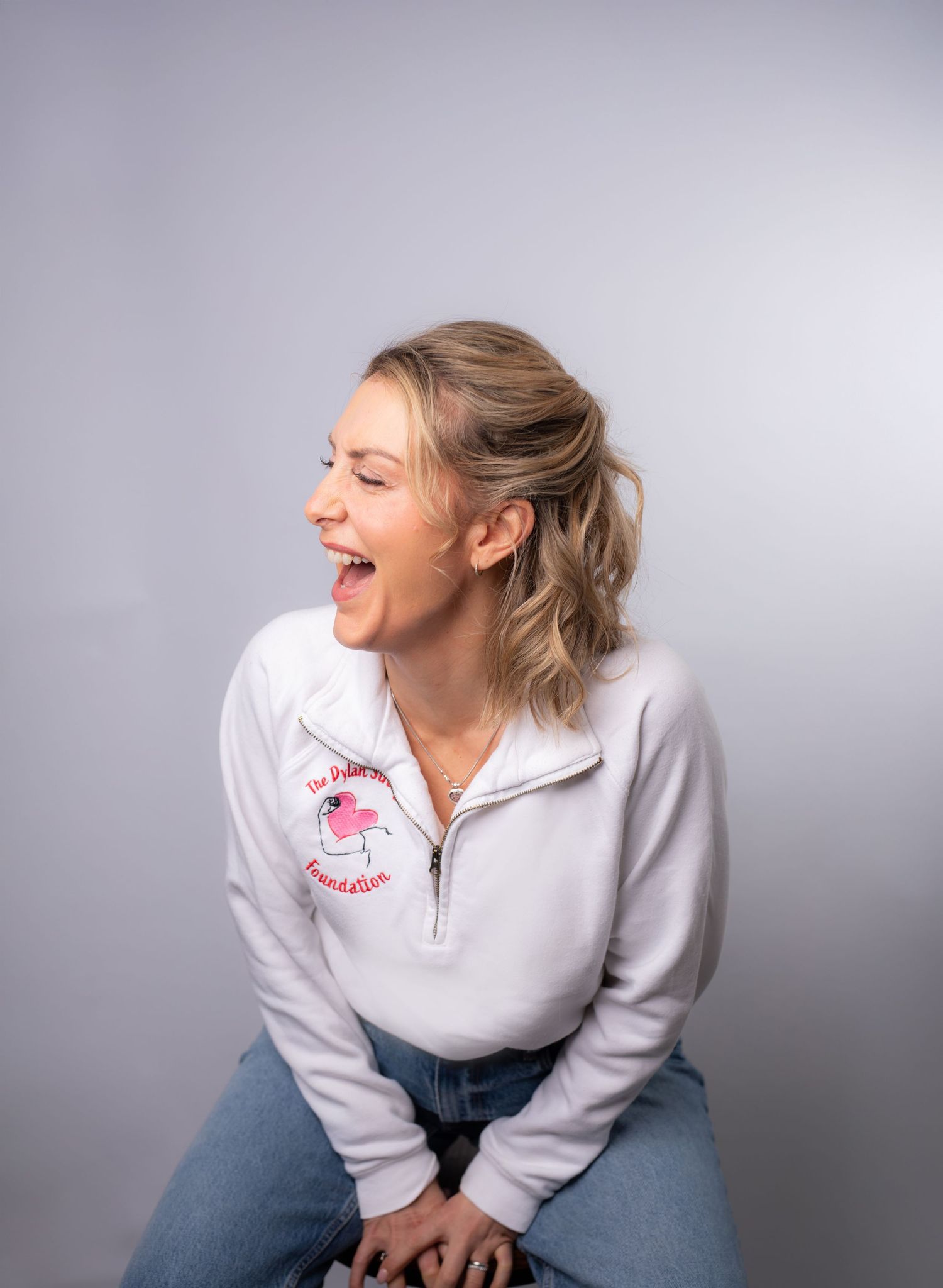A series of expressive poses in a white quarter-zip pullover and jeans against a gray studio background.