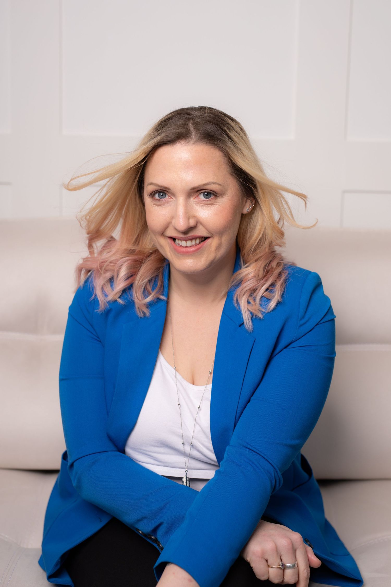 Professional wearing a bright royal blue blazer and white top poses against a light background.