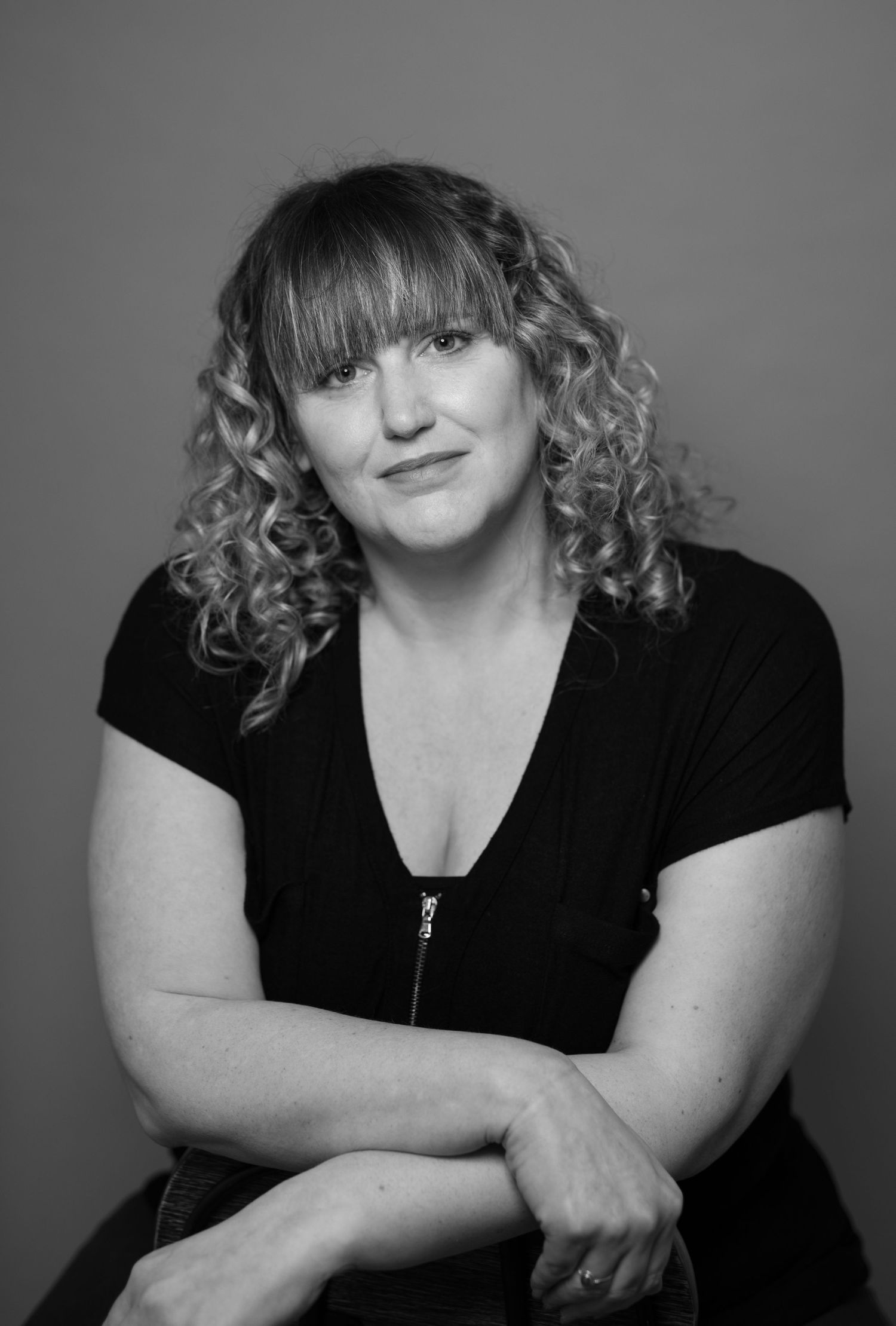 Black and white portrait series showing person in dark top with curly hair against gray background in various poses.
