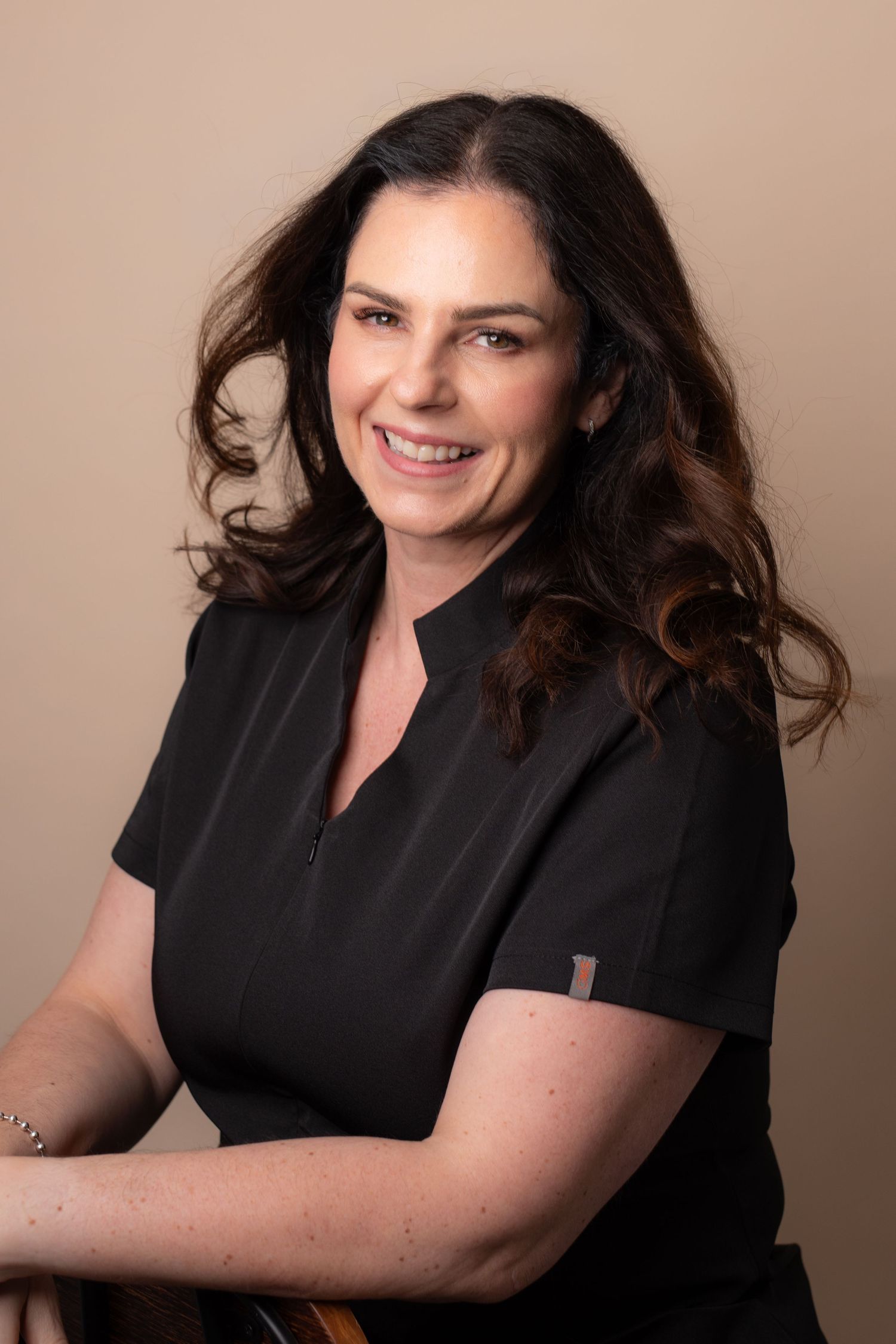 Professional studio portrait series showing person in black top against neutral beige background in various poses.