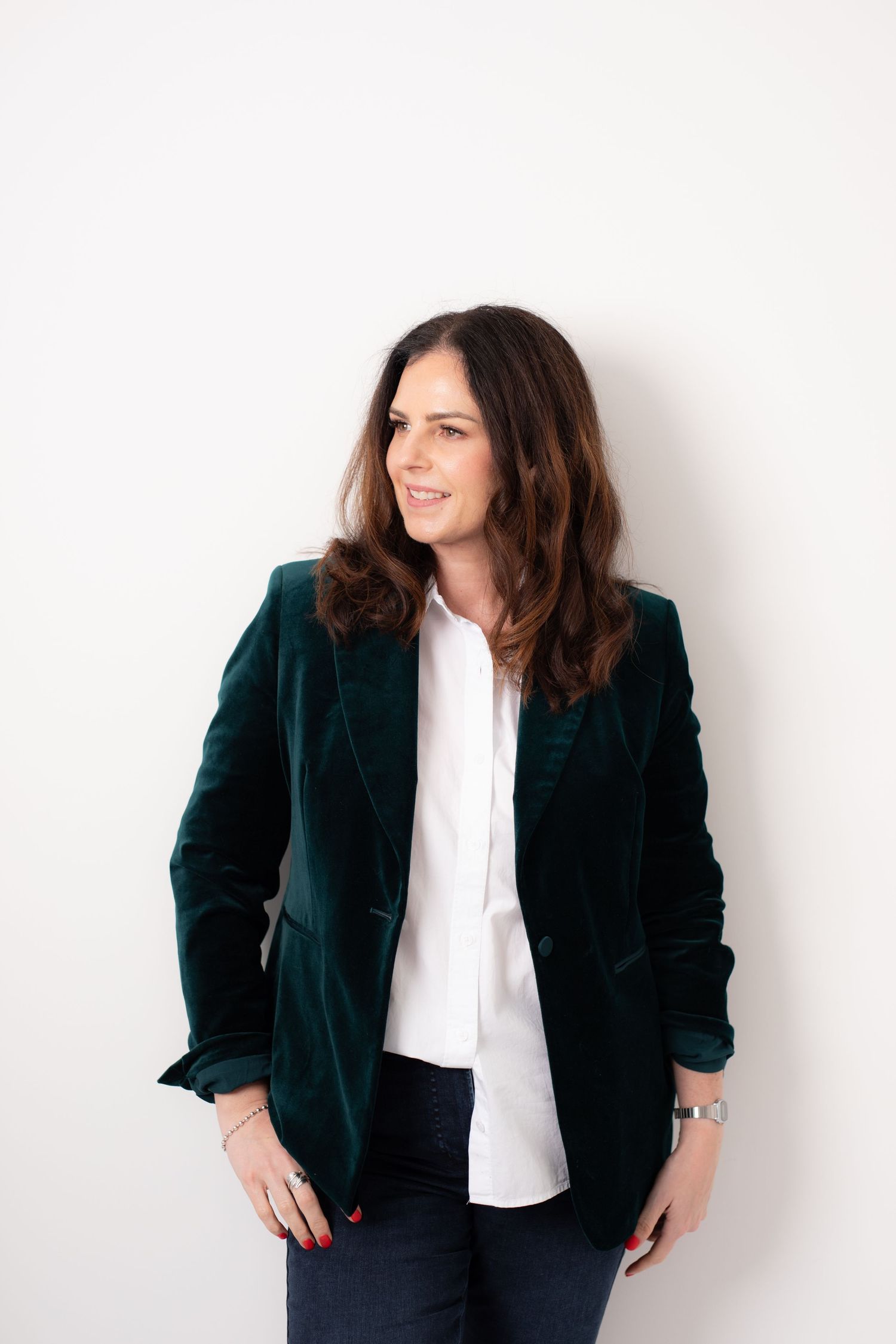 Professional portrait of someone in a dark green velvet blazer and white blouse against a white background.