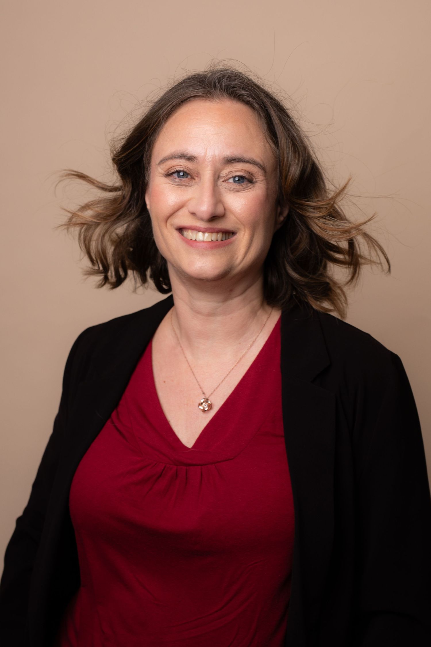 A sequence of professional headshots showing expressions transitioning from neutral to joyful against a beige background.