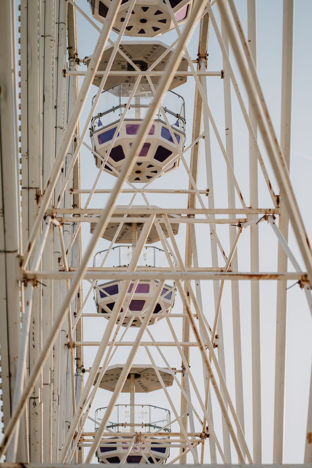 Close-up view of a white Ferris wheel gondolas and structural framework against an overcast sky.