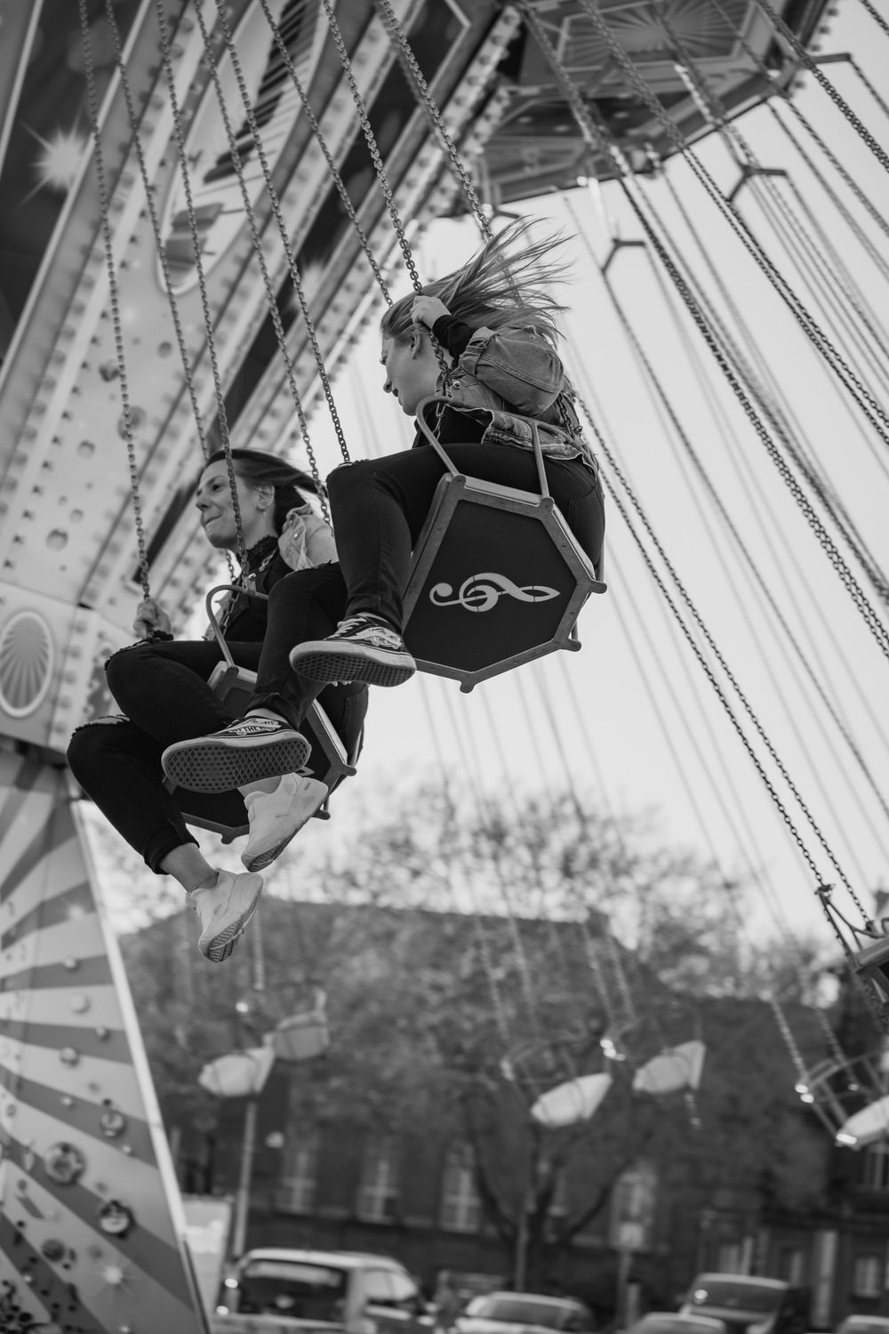 A sequence of black and white photos showing someone swinging higher and higher on a playground swing set.