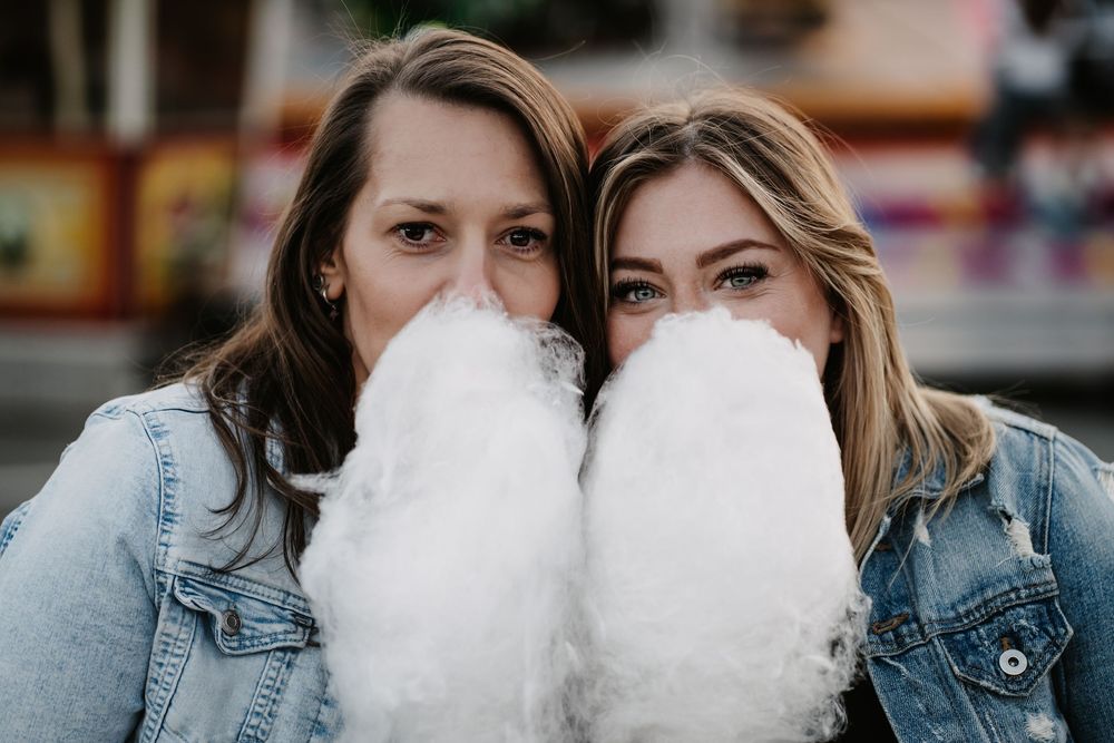 Group of friends enjoying cotton candy together while wearing denim jackets outdoors.