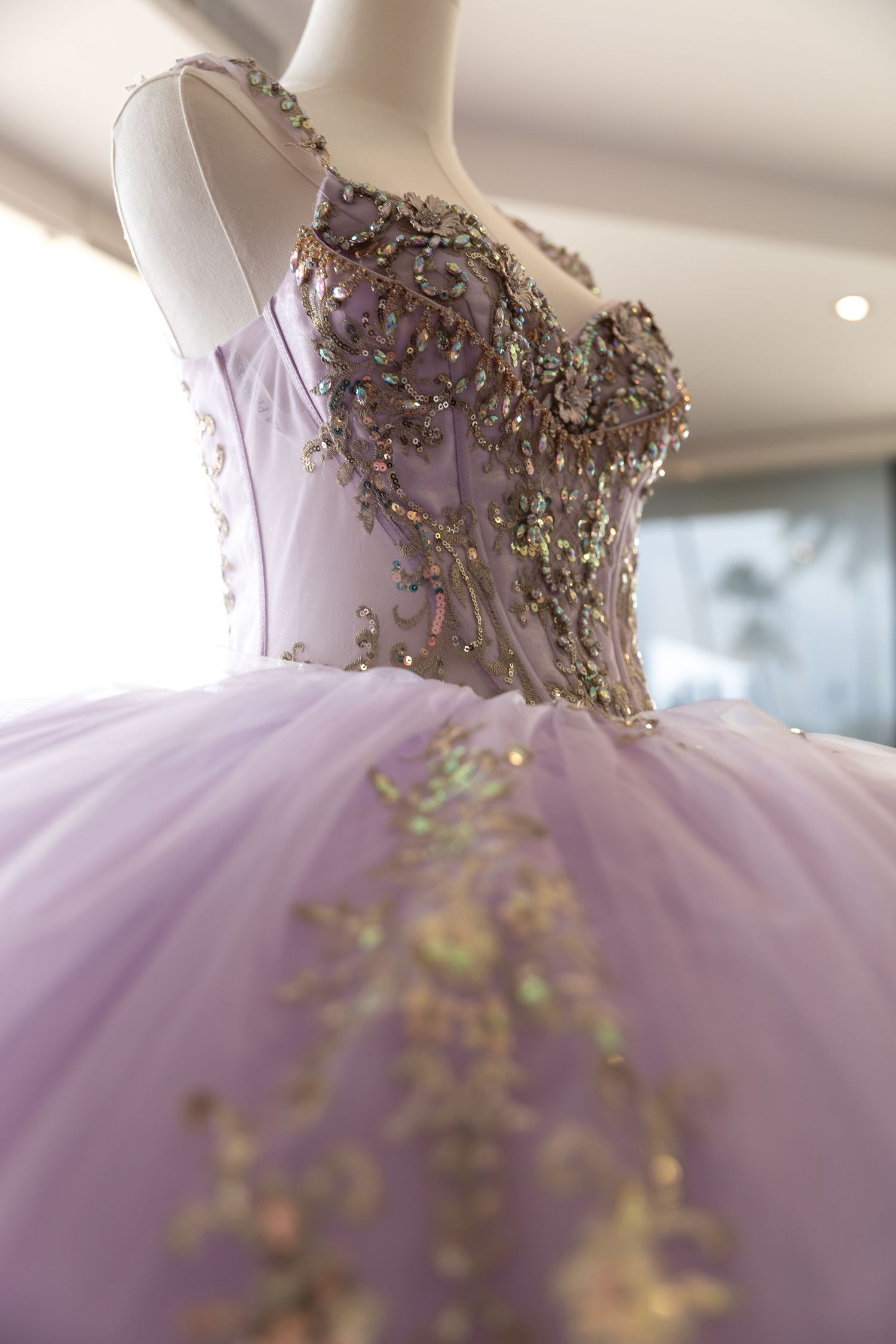 Close-up details of a lavender tulle ball gown with intricate gold beaded embellishments along the bodice.