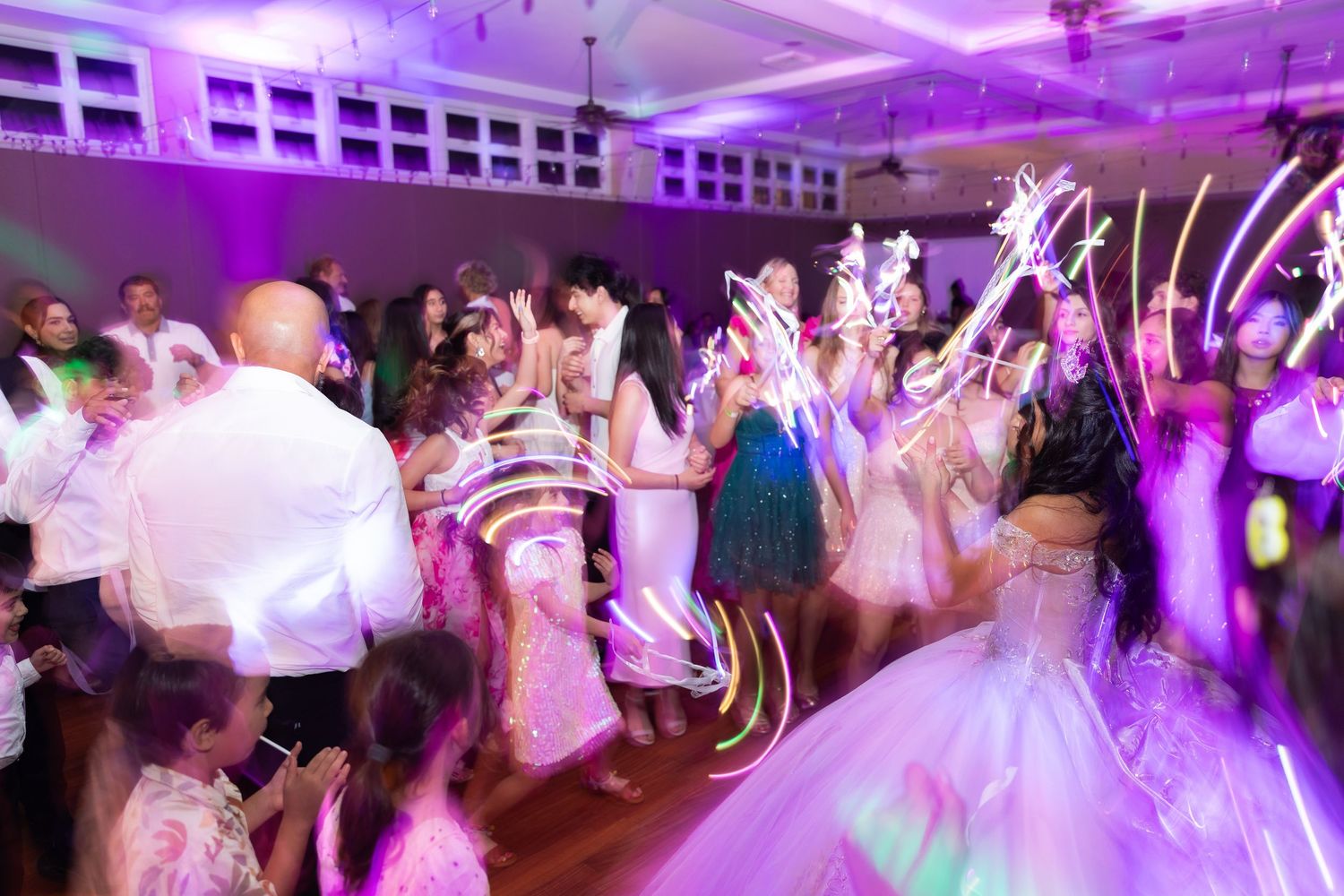 Party guests dancing under vibrant purple uplighting at an elegant indoor celebration.