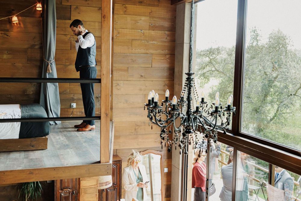 Groom smiling nervously while checking his look in the mirror
