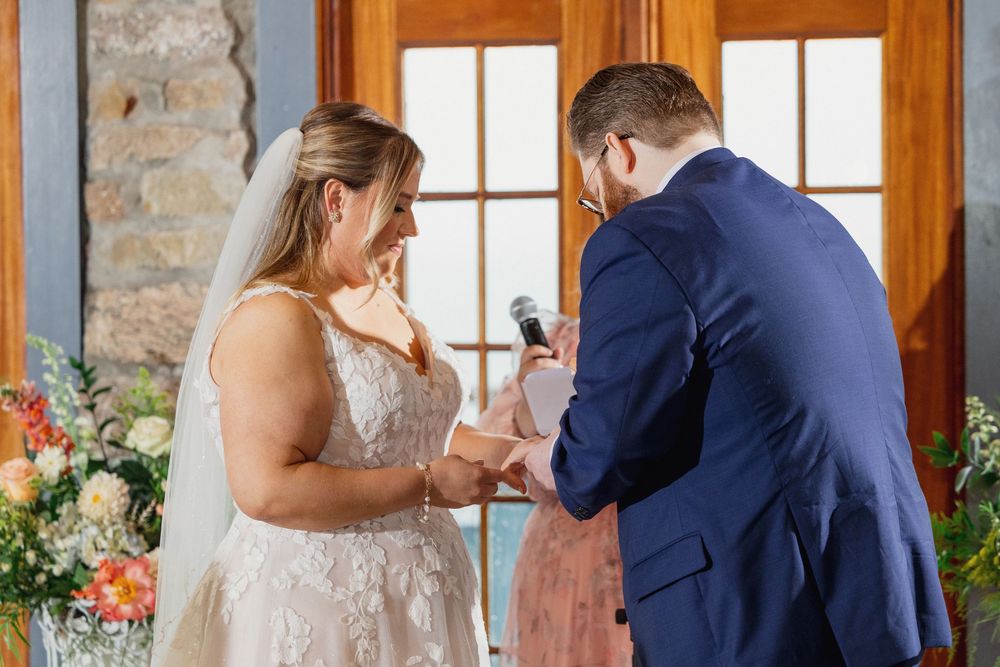 A couple shares a tender moment during their wedding ceremony in a rustic stone-walled venue.