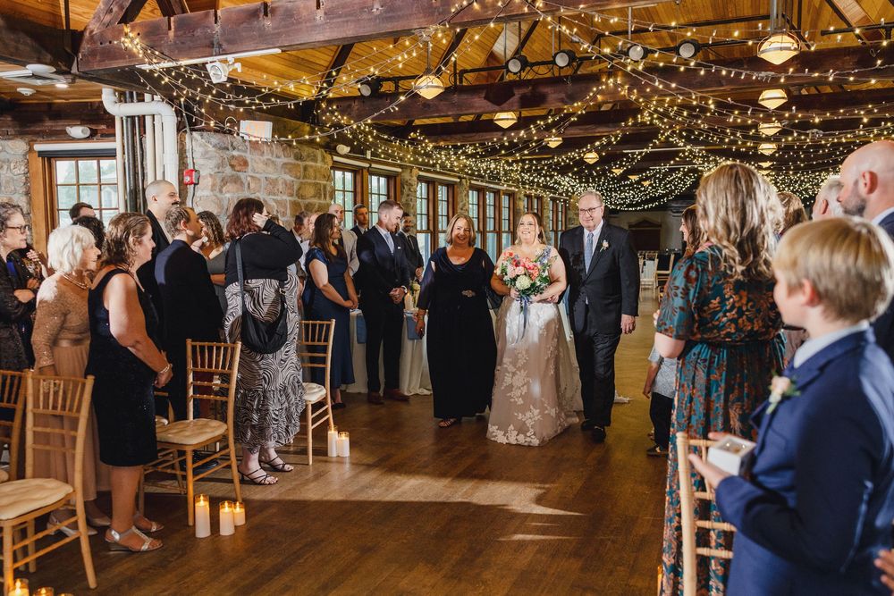 A rustic barn wedding reception venue with string lights and wooden decor filled with guests on the dance floor.