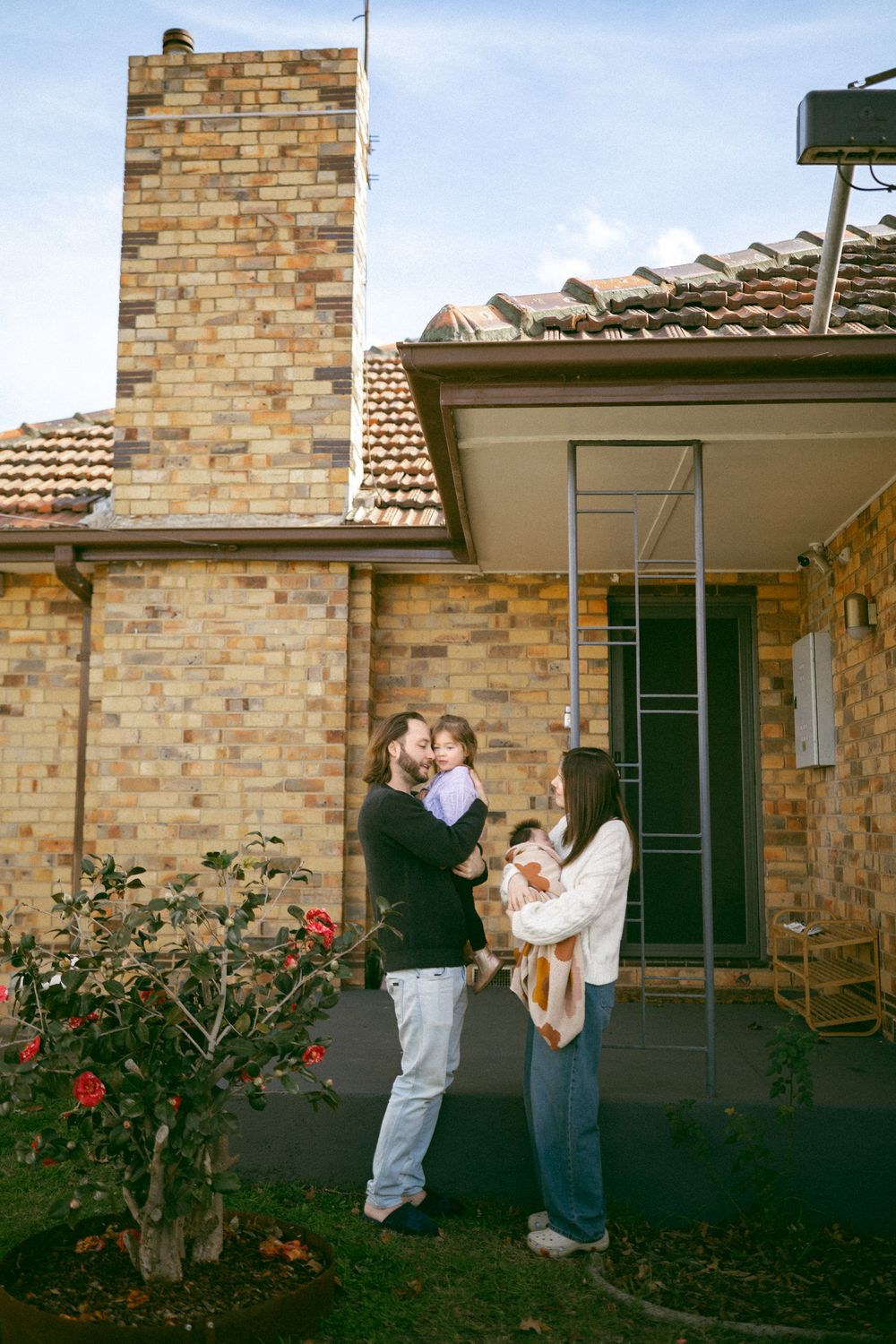 A sequence of four photos showing people dancing and embracing outside a brick house with rose bushes in the garden.
