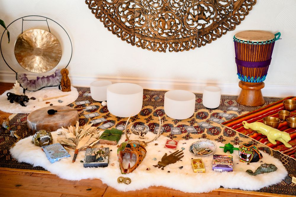 Decorative wooden carvings, crystals, and spiritual objects arranged on a white surface with mystical and healing elements.