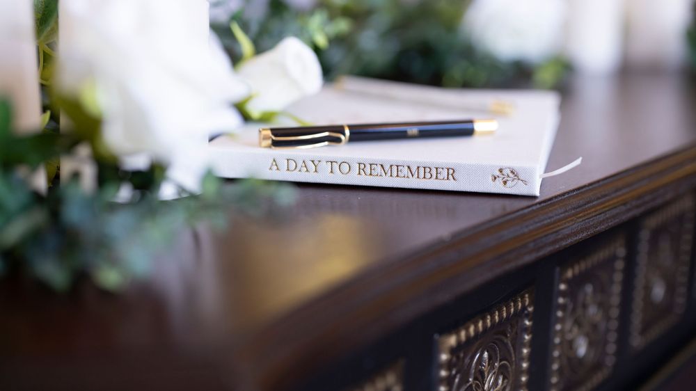 A row of wedding photo albums displayed on a wooden shelf with decorative elements and soft lighting.
