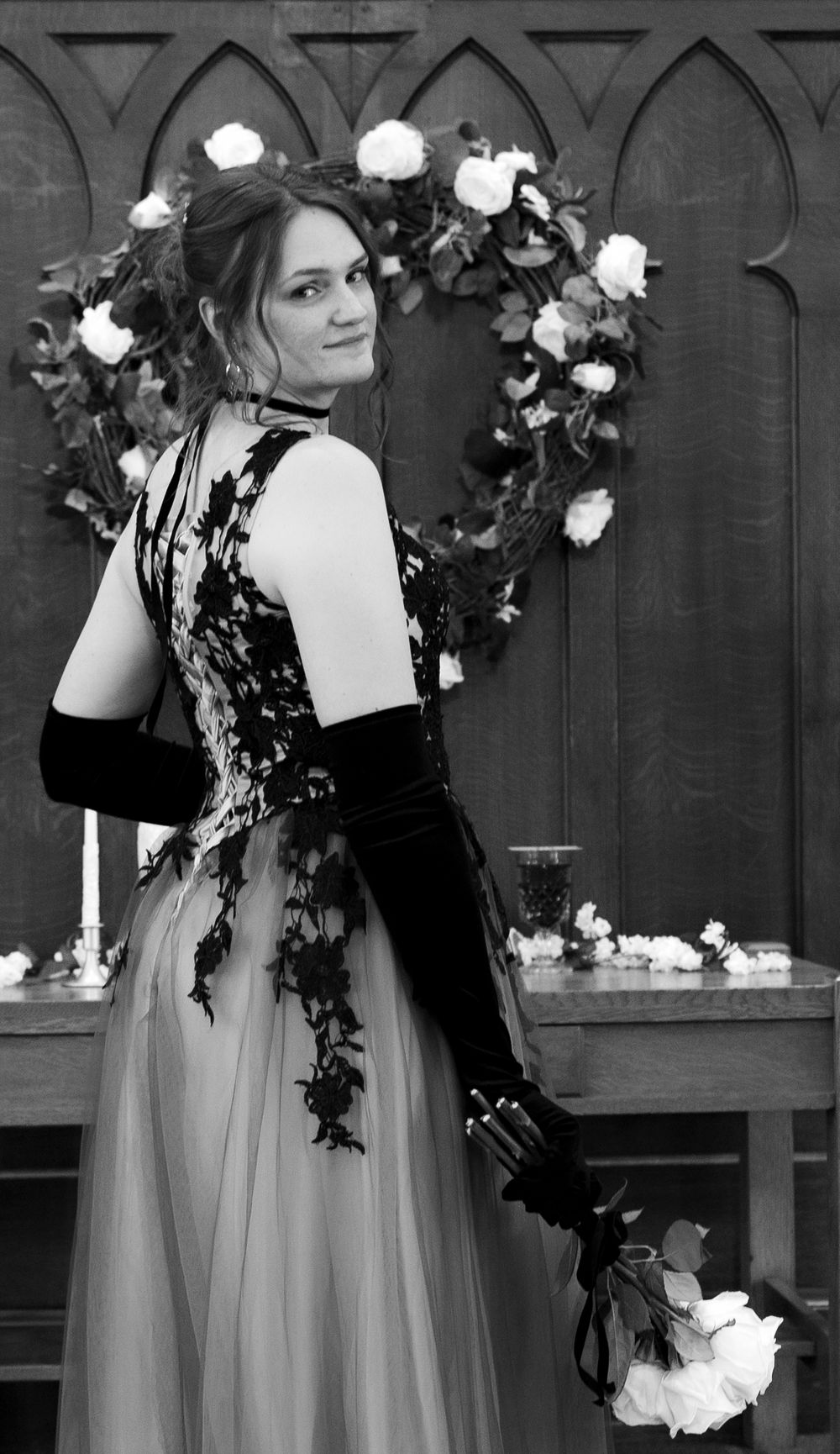 Black and white photo series showing elegant gown with white roses and dark vines against gothic arched backdrop.