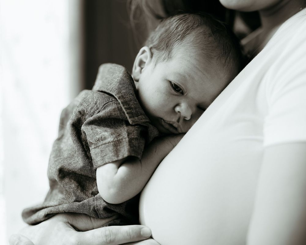 Black and white portrait of peaceful newborn resting against soft white fabric. intimate mother newborn baby photos