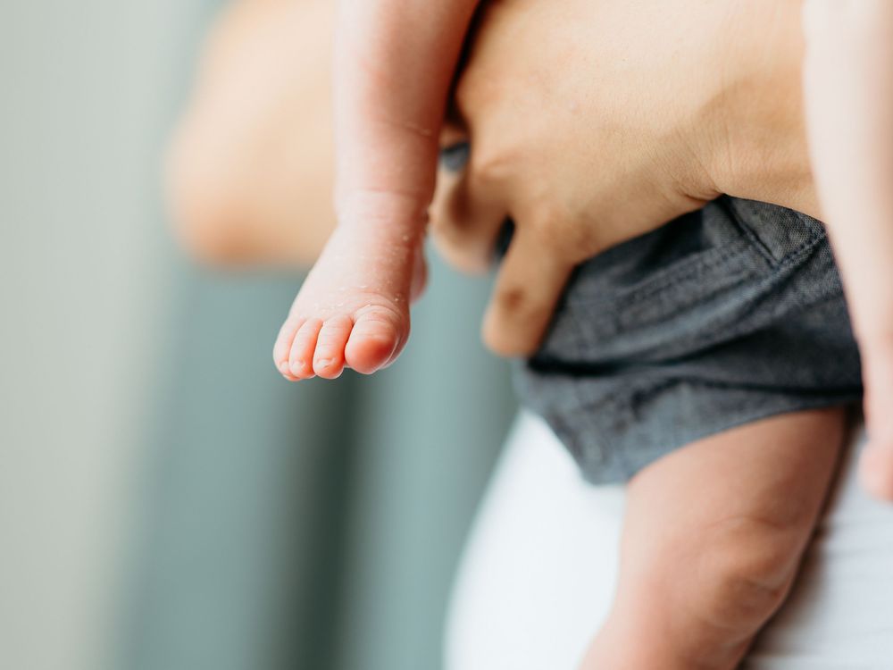 Close-up of tiny baby feet being gently held by caring hands. Central Michigan in-home newborn photo session.