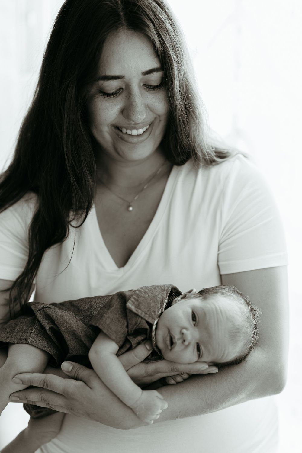 A series of intimate black and white photos showing tender moments between a mother and newborn baby. In-home newborn photos. Michigan.