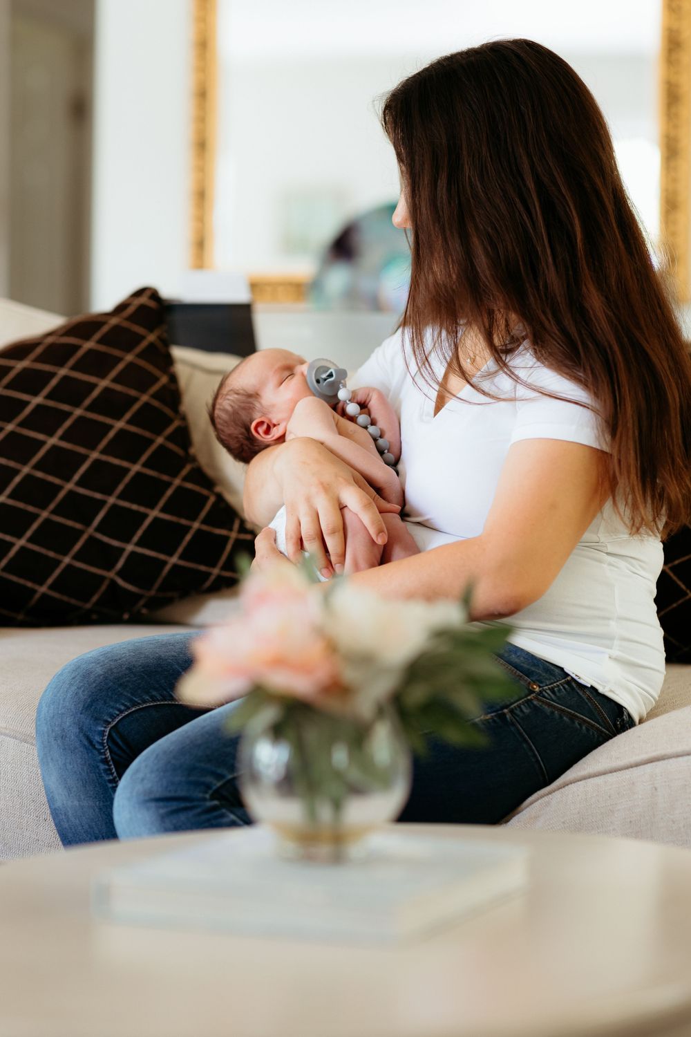 Mother and baby relaxing together on couch in natural window light.