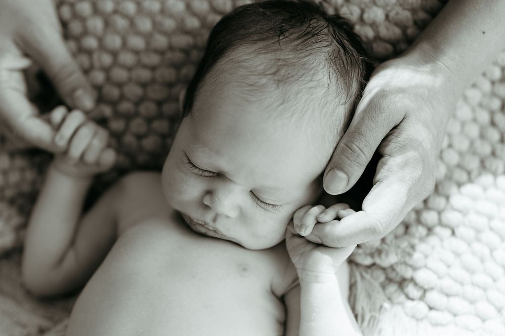 Black and white close-up of sleeping newborn on textured blanket. Newborn photo session in Michigan.