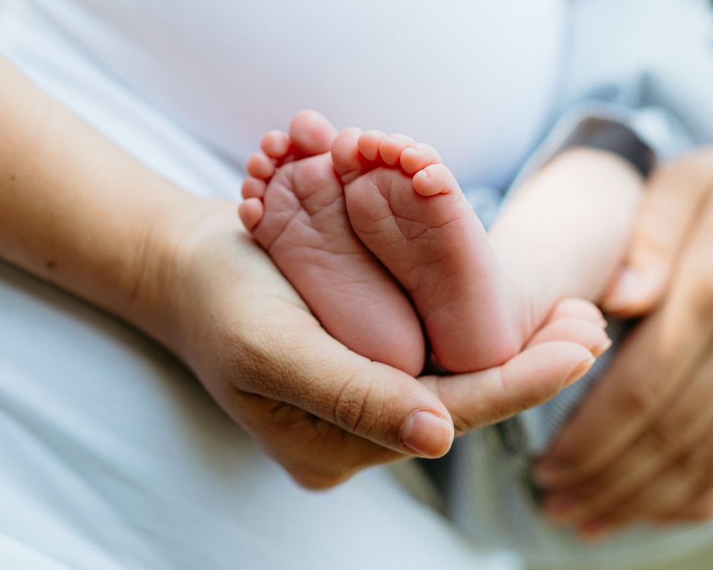 Close-up series of tiny newborn feet being held with gentle care.