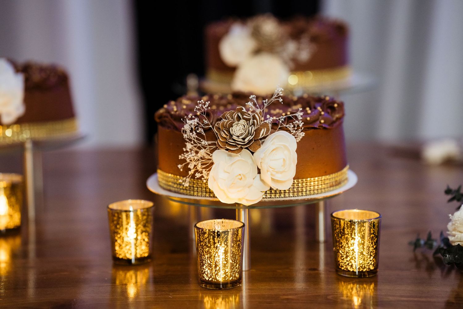 Elegant table settings with glowing candle votives and white floral centerpieces at an evening reception.