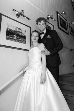 Bride and groom posing on staircase in black and white wedding portrait indoors.