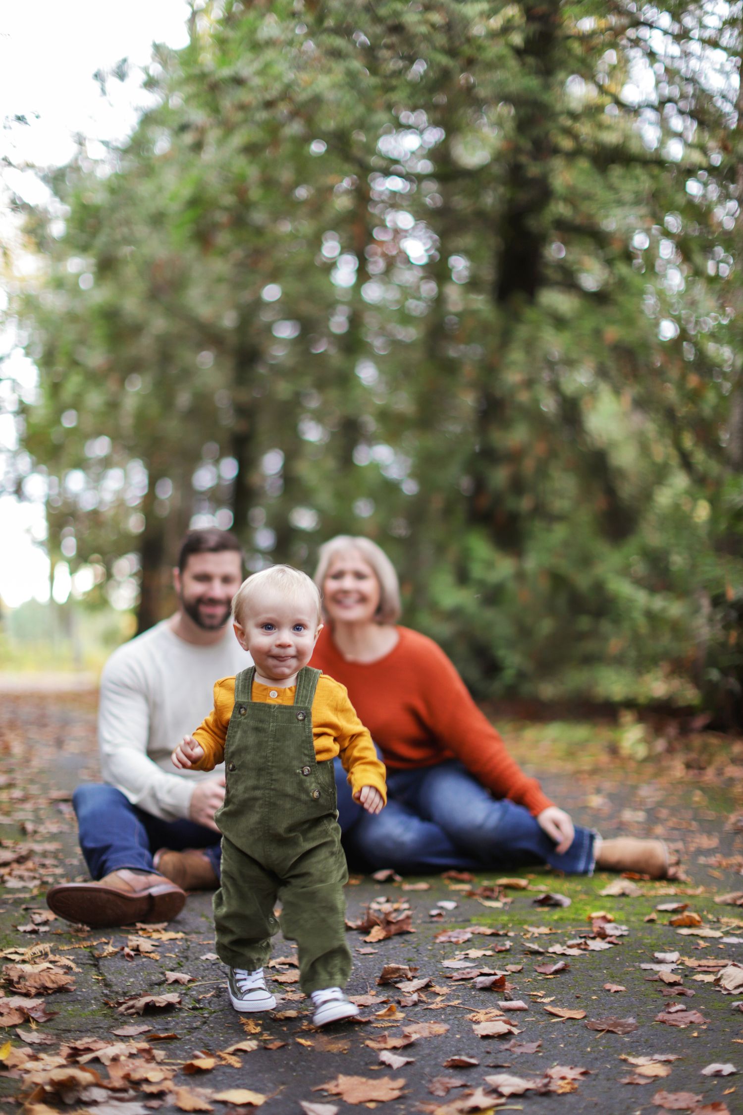 A family wearing coordinated outfits poses together in a sunlit autumn forest setting.