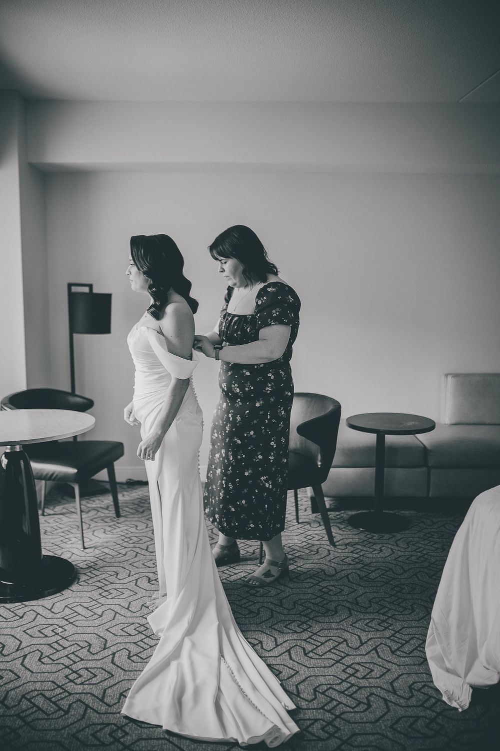 Black and white photo sequence showing a bride getting dressed and helped into her wedding gown in a hotel room.