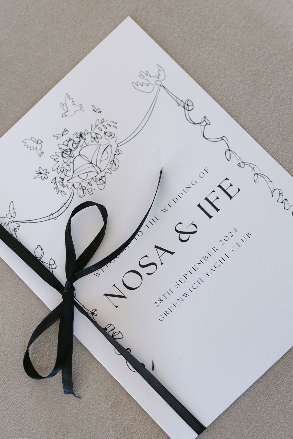 Elegant white wedding invitations with black ribbon bows displayed in a sequence on a gray surface.